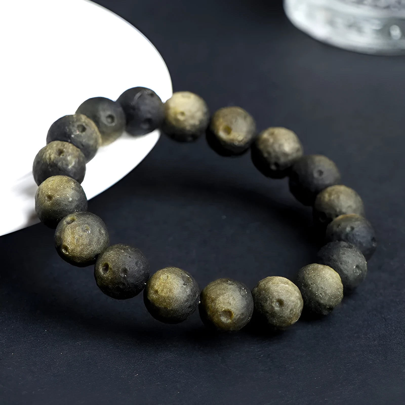 Close-up of an obsidian crater ball bead bracelet in a gold meteorite finish, showing its textured spherical beads.