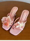 Women's handmade asymmetric flower high-heel sandals in black with a square toe and calf leather upper.