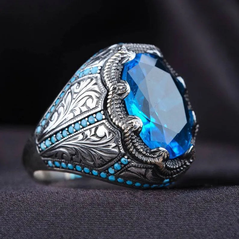 Geometric antique silver unisex ring with a central blue zircon stone on a finger.
