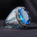 Geometric antique silver unisex ring with a central blue zircon stone on a finger.