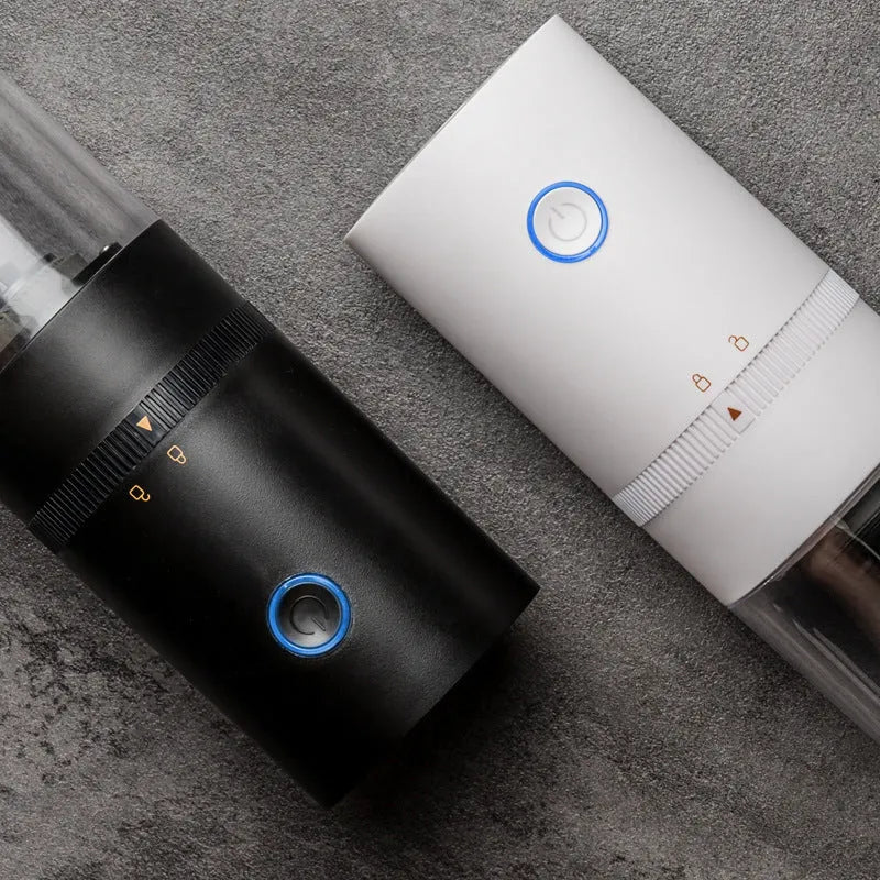 Black and white portable USB-C electric coffee grinder with transparent chamber on a kitchen counter