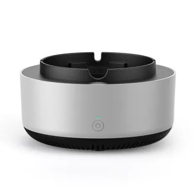 Grey electronic air purifier ashtray with cigarette butt grooves on a table