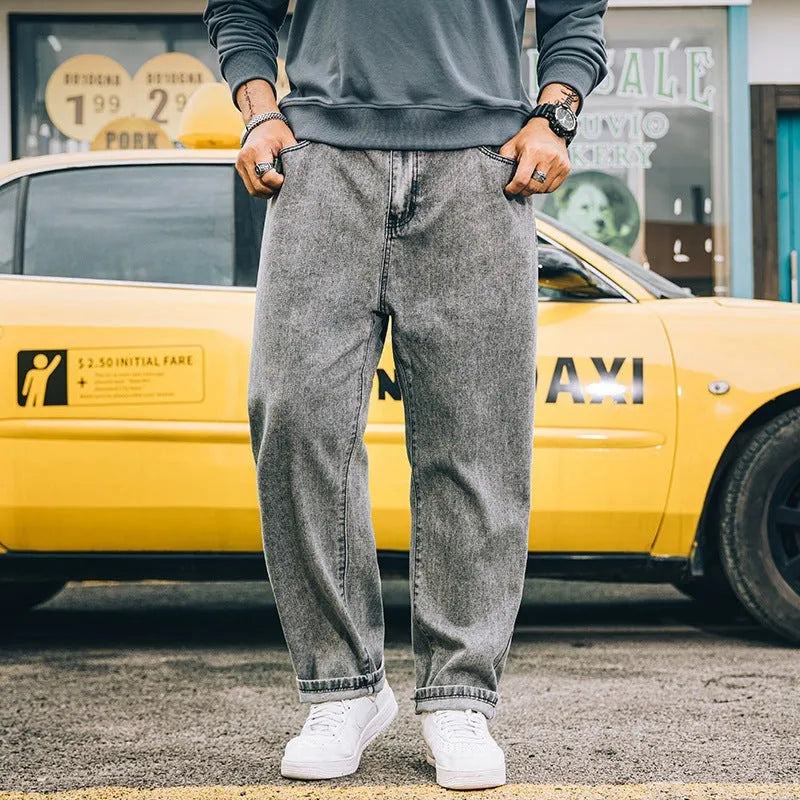 Man wearing dark blue loose straight-leg cotton jeans with a simple design and zipper fly.