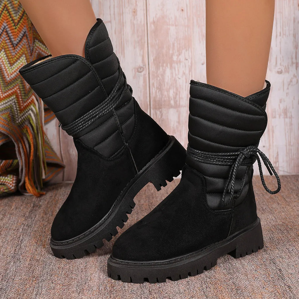 Women's black chunky heel snow boot with suede upper and lace-up design.