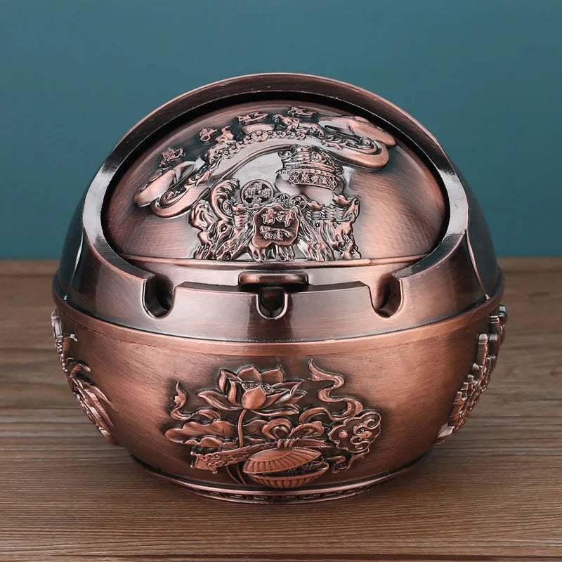 Bronze and red copper alloy decorative ashtray with smoke-extinguishing slot on a table.