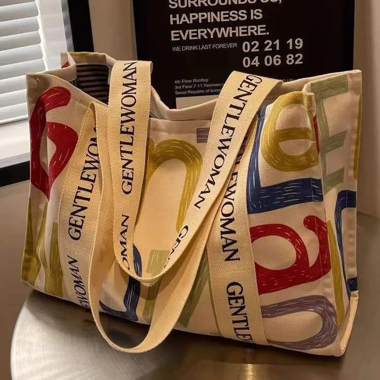 Canvas women's travel tote bag with printed design options including black letters, coloured letters, and pattern styles
