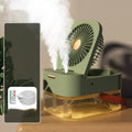 White or green USB desktop humidifier fan with remote control on a wooden desk.