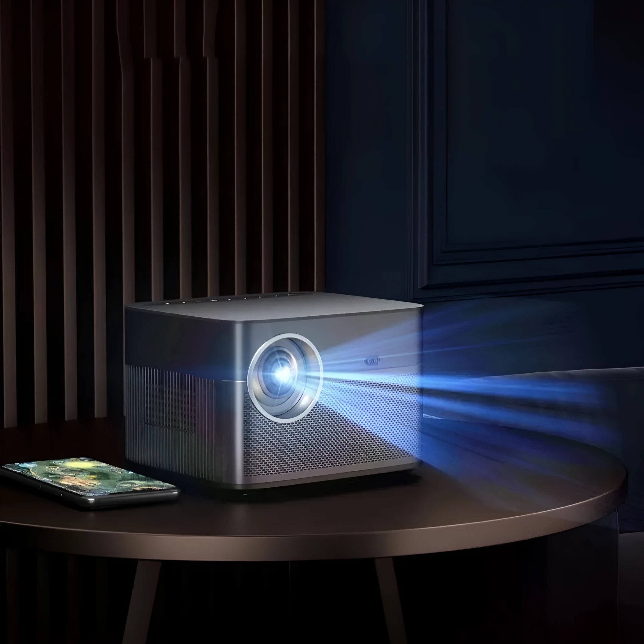 Silver portable 1080P home projector projecting a 100-inch image in a dark bedroom