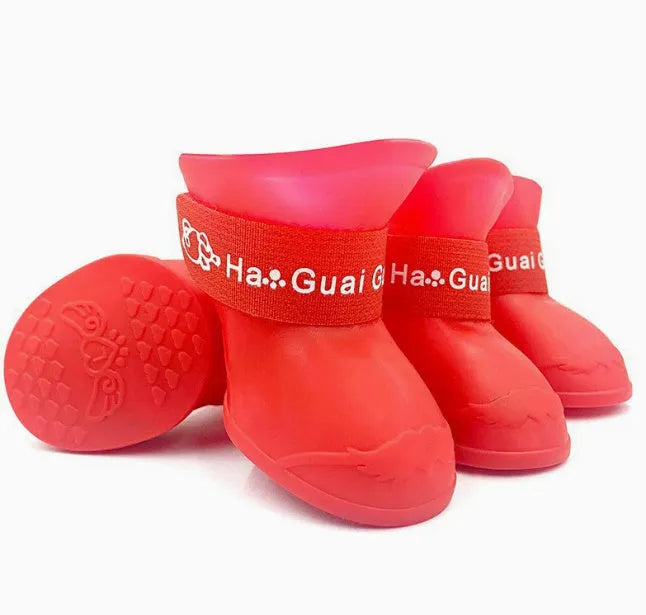 Set of four colourful rubber dog rain shoes with anti-slip soles on a wet surface.