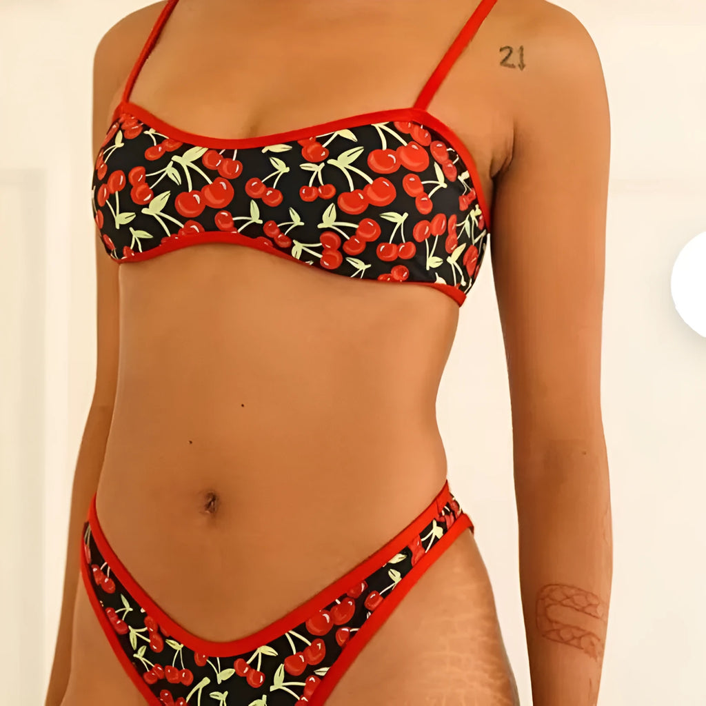 Women's cherry and floral print bikini swimsuit set with tube top and briefs on a neutral background.