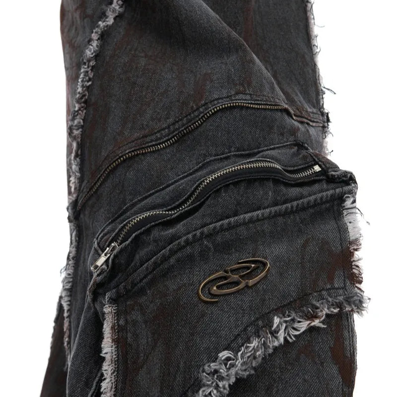 Black raw-edge splash-dye distressed denim coat with padded shoulders and matching trousers on a hanger.