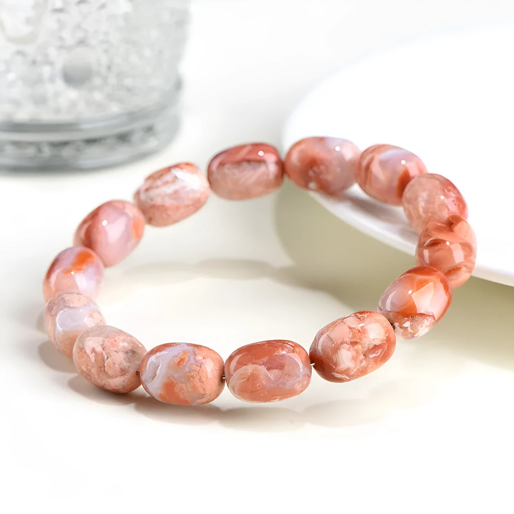 Natural cherry agate barrel bead bracelet with Ruyi charm on a wrist.