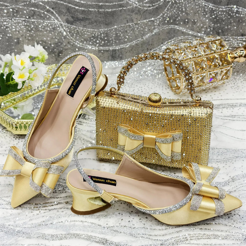 Women's black pointed toe sandals with square buckle and matching rhinestone bag on a mid-height wine glass heel.