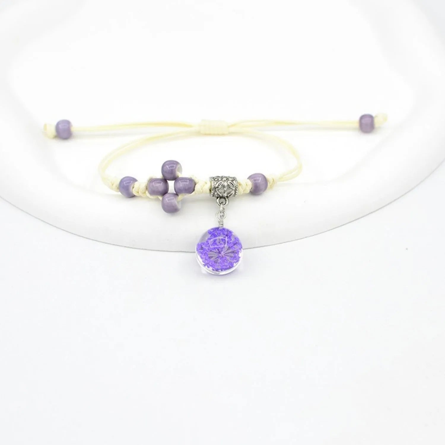 Close-up of a hand-woven glass bracelet with large 1.4cm beads containing real dried flowers and lace floral detailing.