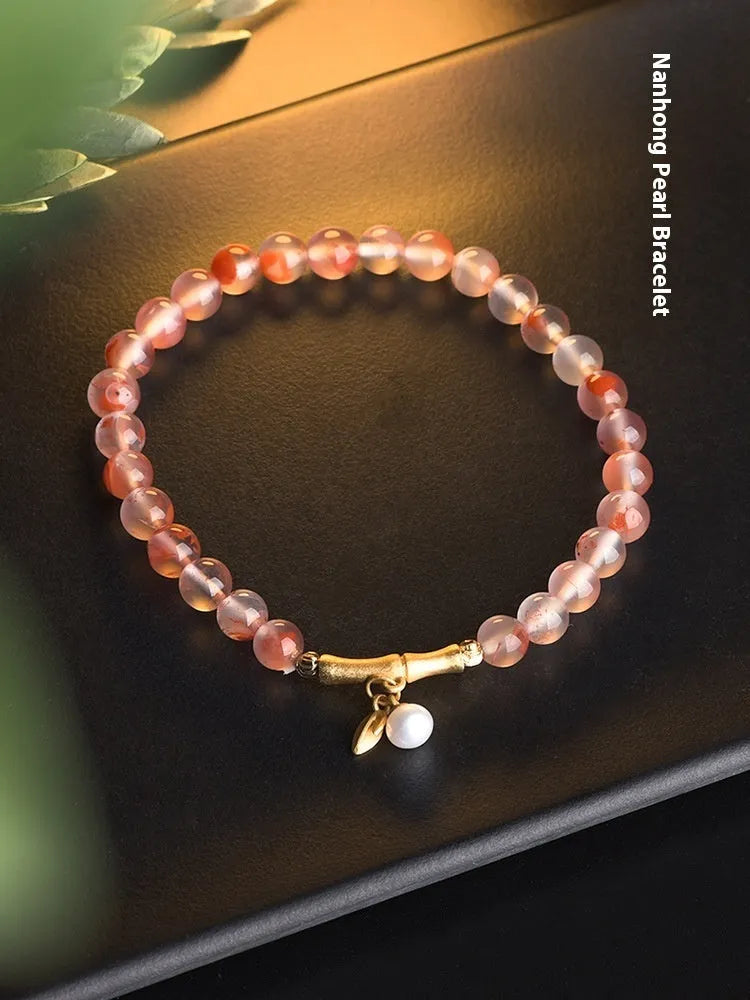 Polished Nanhong agate bracelet with ethnic bamboo-joint and flower design on a wrist.