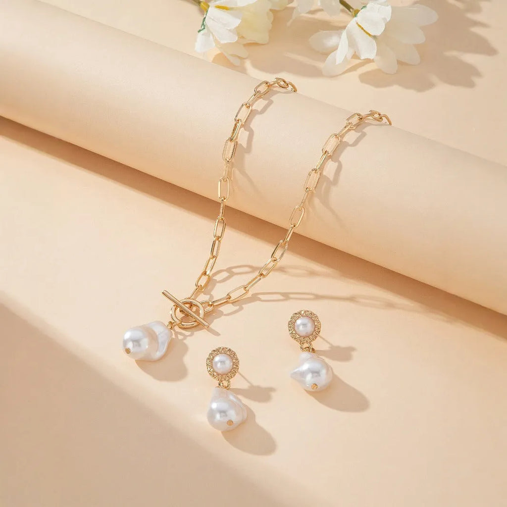 Gold baroque pearl pendant necklace and matching ear stud jewellery set on white background