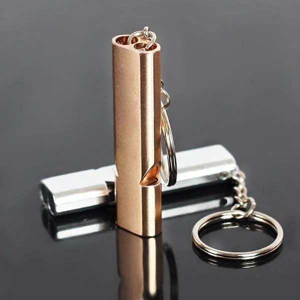 Close-up of a silver aluminium alloy double-hole outdoor survival whistle on a dark background.