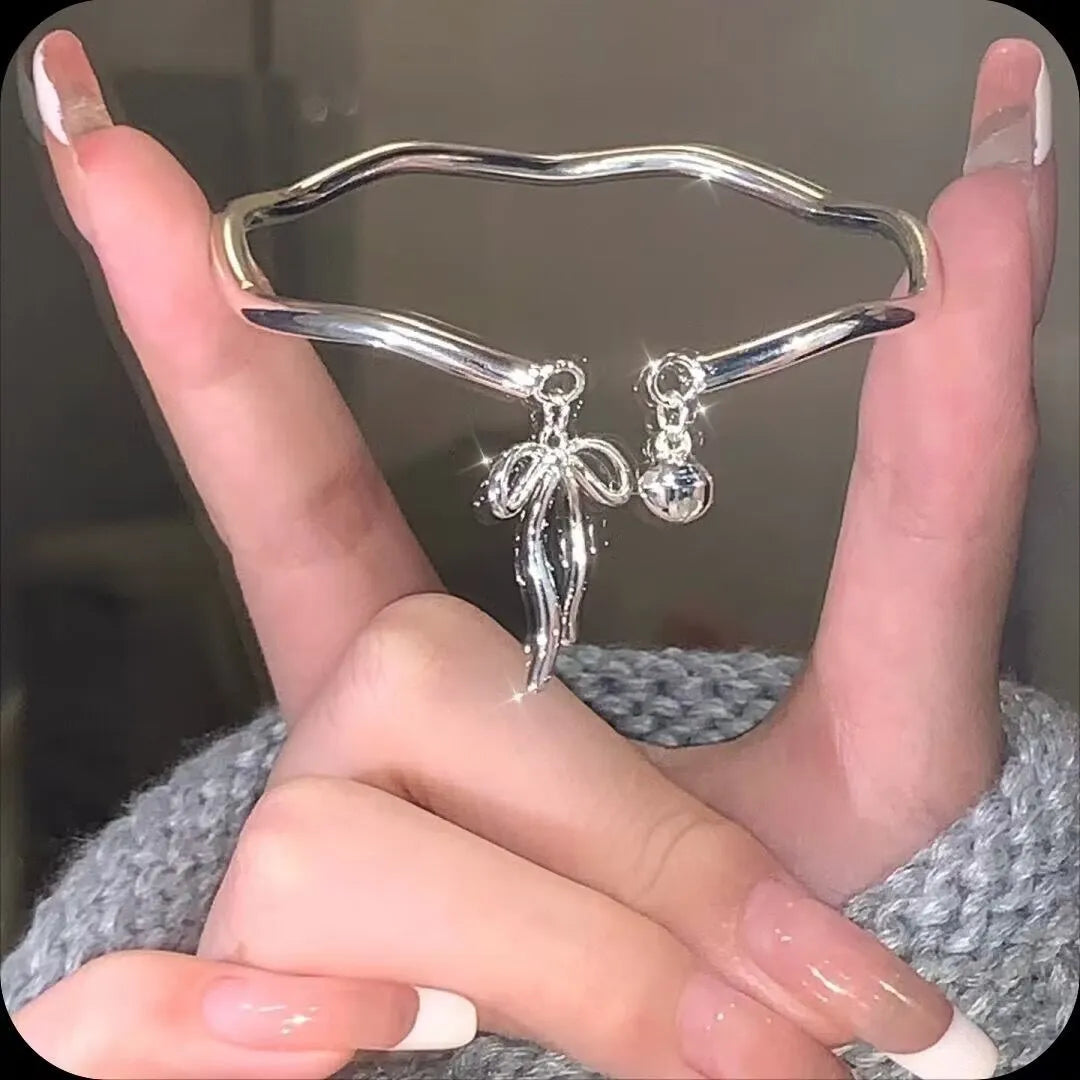 Silver adjustable bracelet with a detailed bow charm on a model's wrist, showing the adjustable clasp.