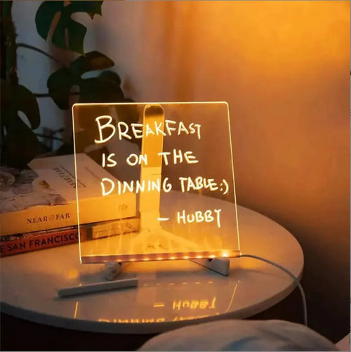 Acrylic DIY LED message board on a bracket, glowing softly with handwritten notes, alongside white and colourful pens.