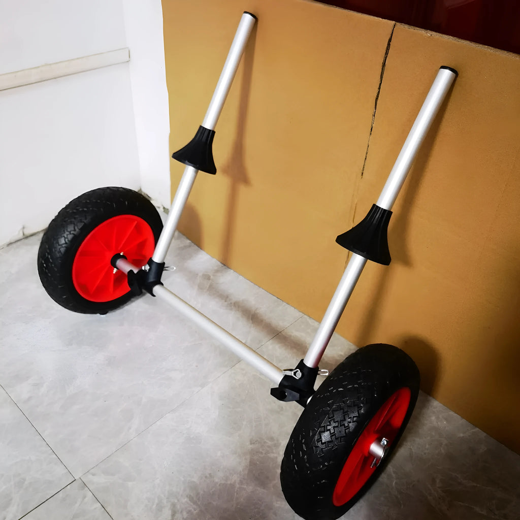 Foldable aluminium kayak handcart with rubber cradle, shown carrying an open kayak on a beach.