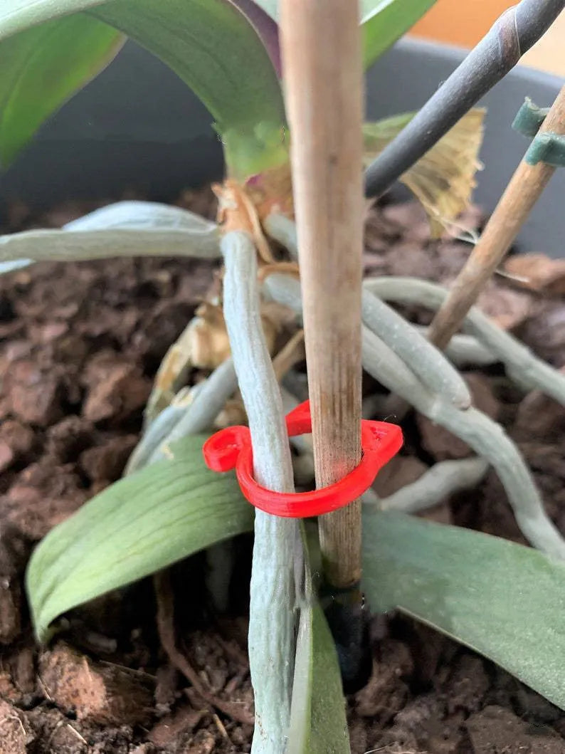 A colourful cat-shaped plastic clip for securing plant stems in the garden.