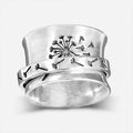 Silver-coloured rotatable flower fashion ring on a finger, showing the floral detail.