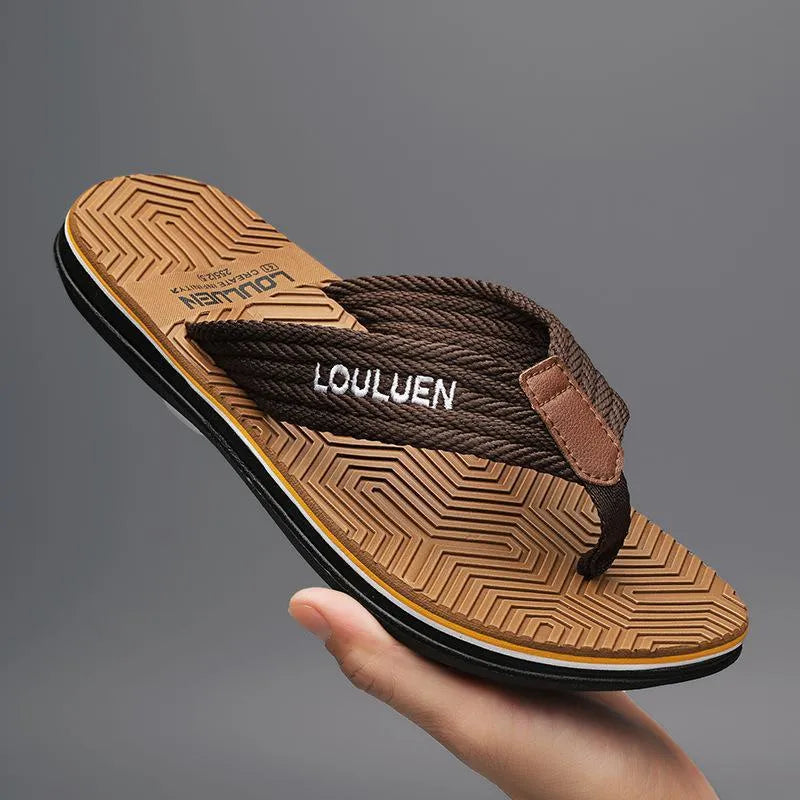 Men's black flip flops with textured non-slip sole on a beach background.