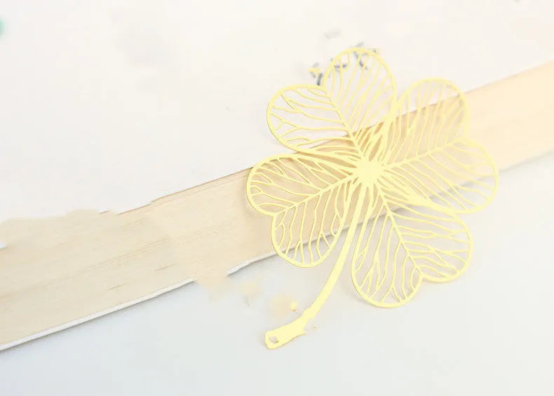 Detailed brass bookmark with hollow maple leaf pendant and rose gold tassel on a book page.