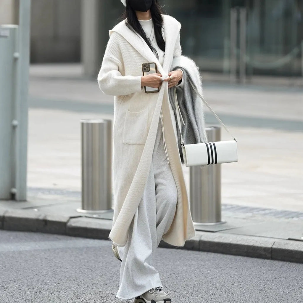 Long grey knitted women's cardigan with hood and trench coat design, shown open as a front-fastening garment.