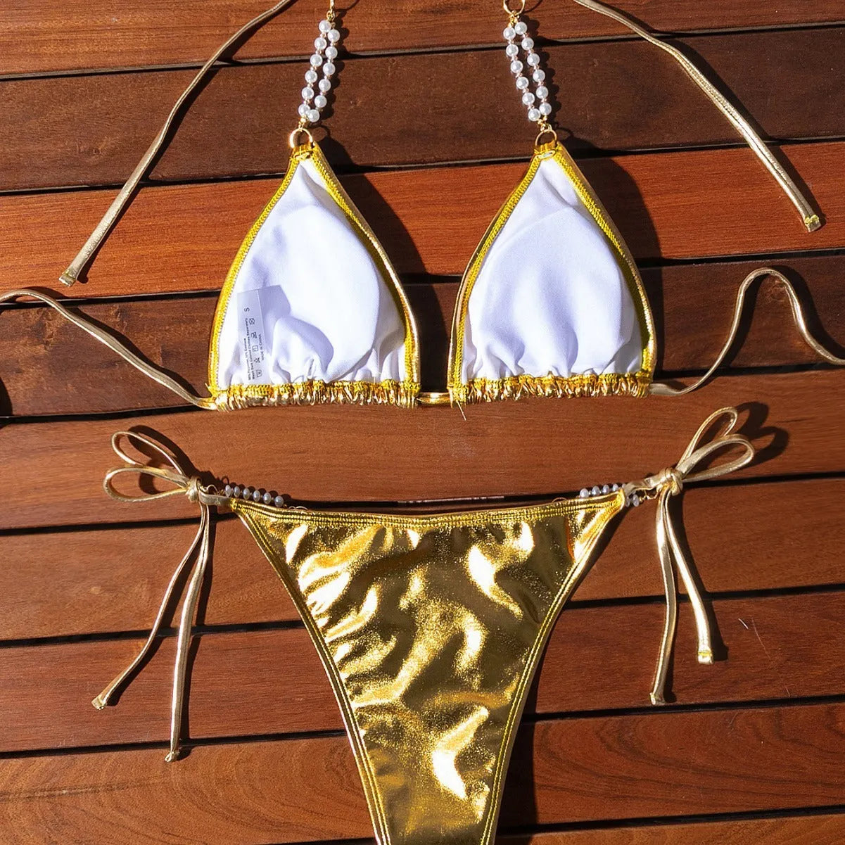 Gold women's halter lace-up bikini swimsuit with pearl chain detailing on mannequin