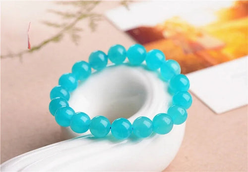 Natural blue-green Grade 7A Amazonite scattered beads in various sizes next to a finished crystal bracelet.