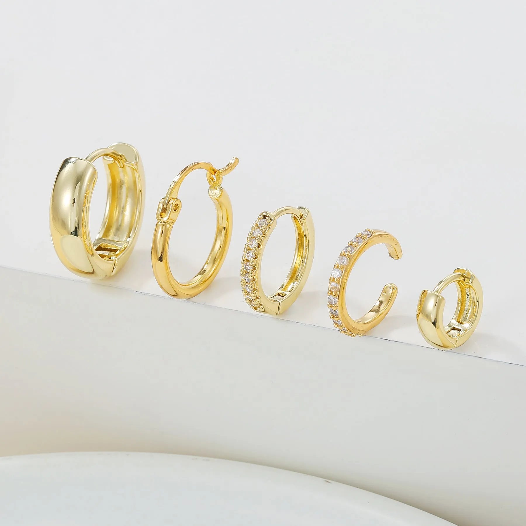 Five round copper earrings with inlaid zircon in gold and white gold colours