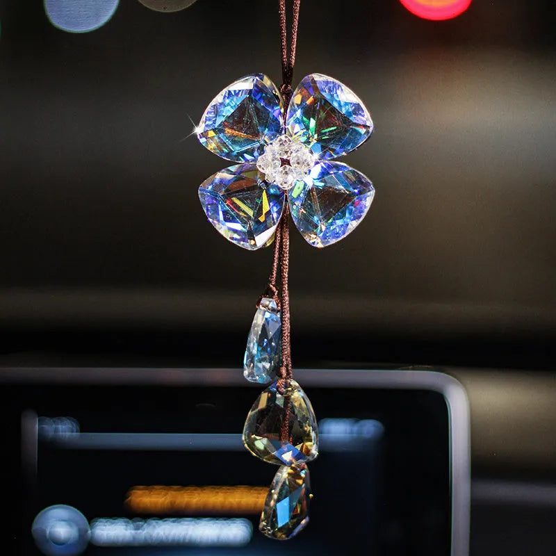 Crystal four leaf clover car pendant hanging, shown in one of four colour options: transparent, champagne, translucent black, or extremely shiny.