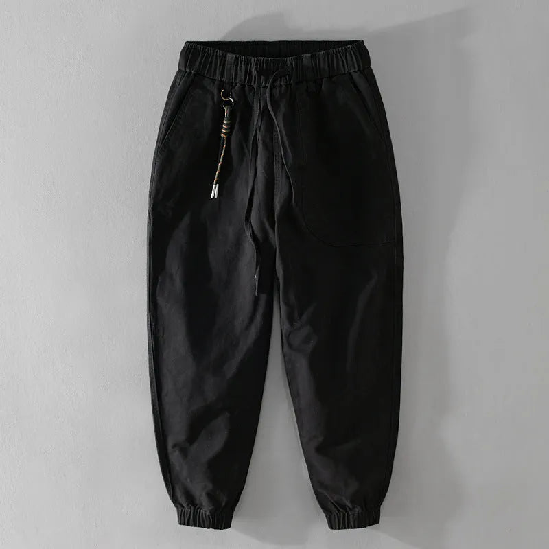 Men's army green cotton drawstring overalls with ankle bands laid flat.