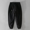 Men's army green cotton drawstring overalls with ankle bands laid flat.