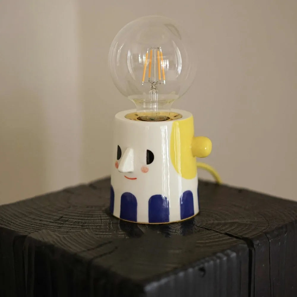 Handmade solid ceramic table lamp with a white spherical headlight shade on a bedside table.