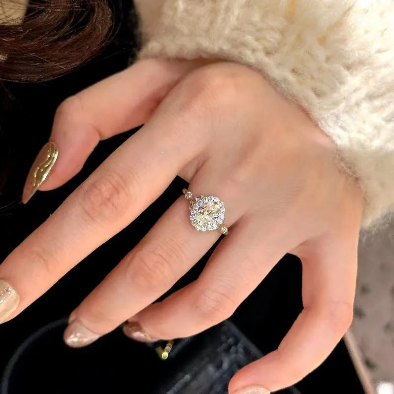 Close-up of a silver geometric ring with a large elliptical diamond on an adjustable open band.