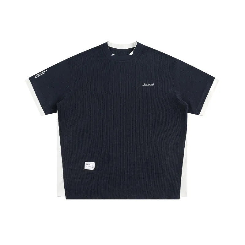 Loose grey waffle-texture T-shirt with embroidered retro alphabet design on the front.
