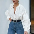 White women's button front long sleeve loose fit polyester shirt on plain background