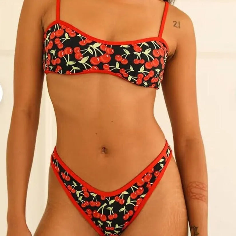Women's cherry and floral print bikini swimsuit set with tube top and briefs on a neutral background.