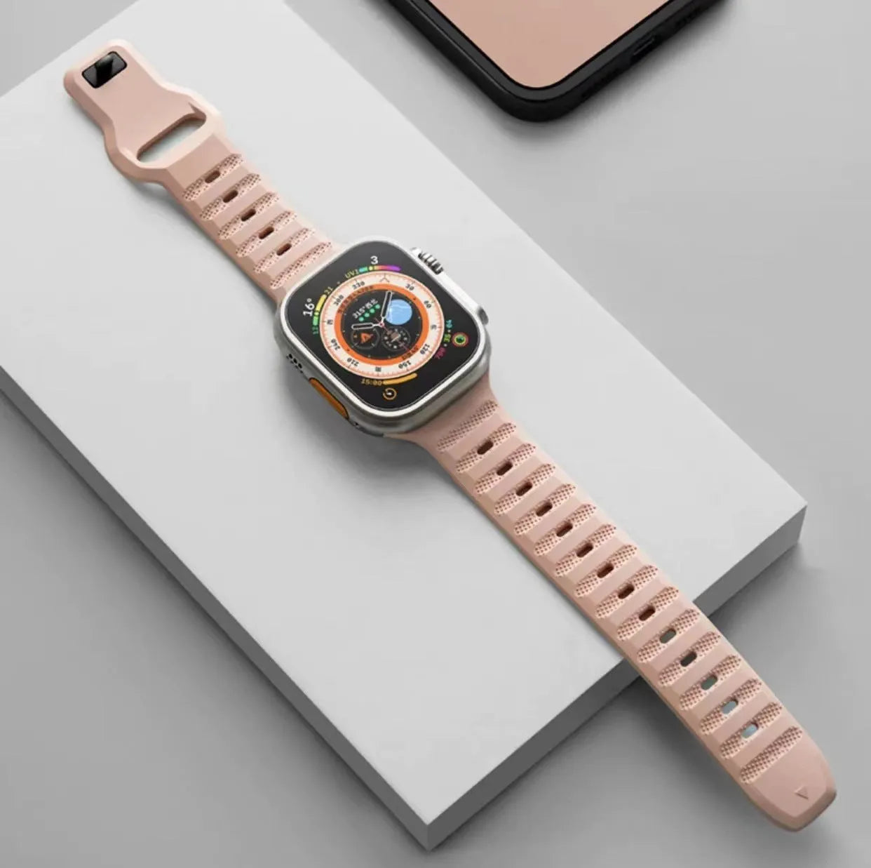 Black fluoro rubber Apple Watch band with T-buckle closure on a wrist, showing compatible Ultra model.