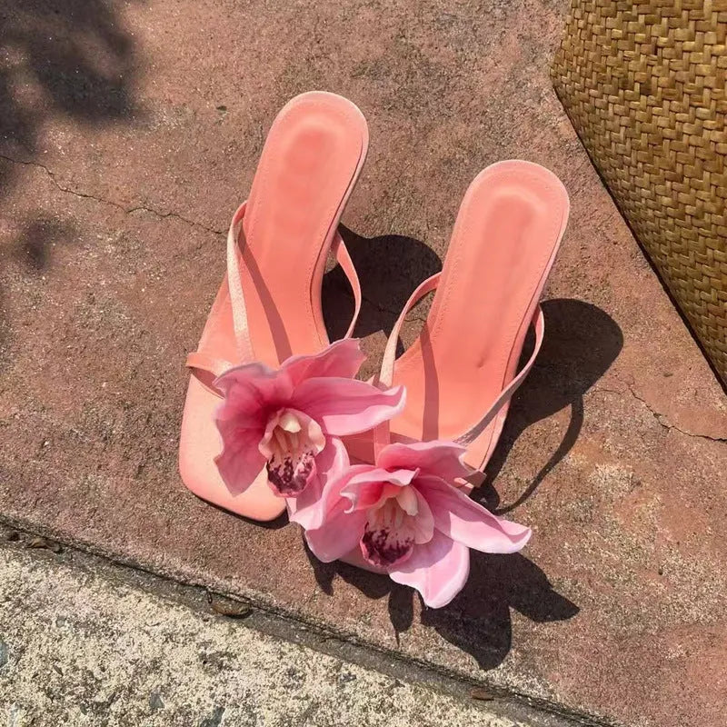 Pink satin women's high heel sandals with a square toe and a white artificial flower decoration.