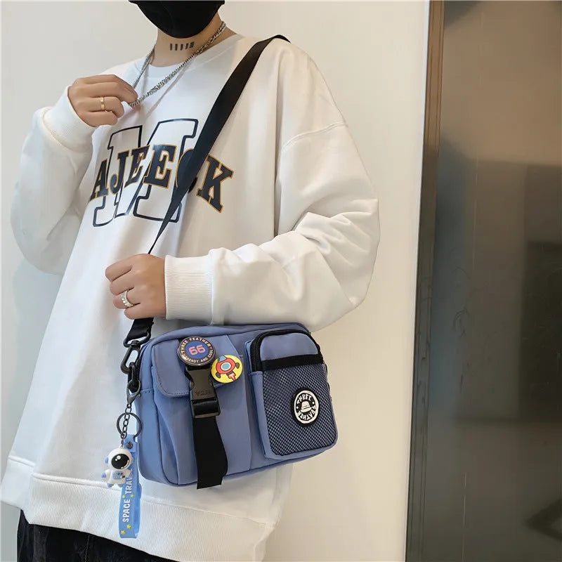 Casual nylon messenger bag for men and women, 22 x 6 x 17 cm, in black milky white grey or blue with two badge pendants
