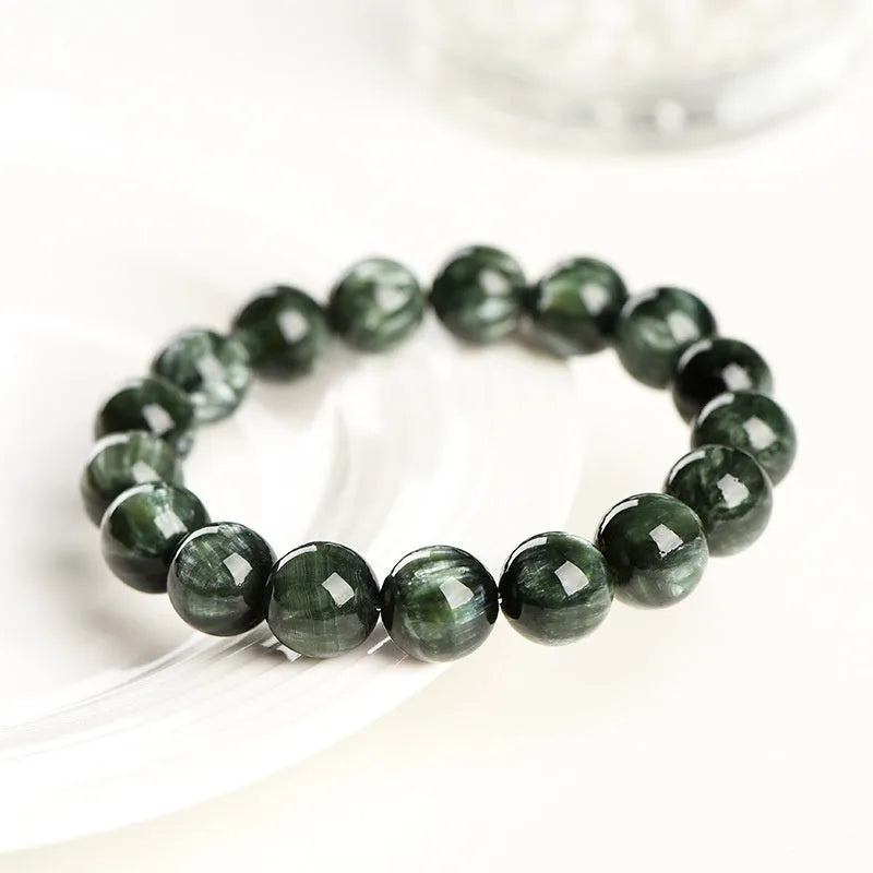 Natural green dragon crystal bead bracelet with geometric ruyi pattern on white background.