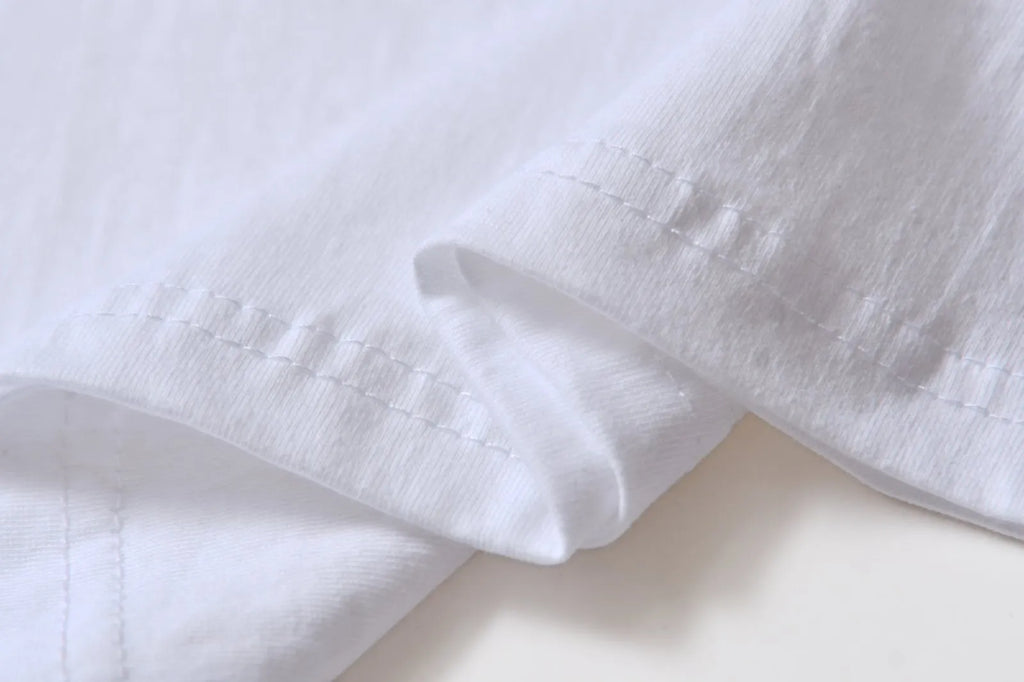 White cotton T-shirt overalls with a round neck and short sleeves, shown in a loose pullover style.
