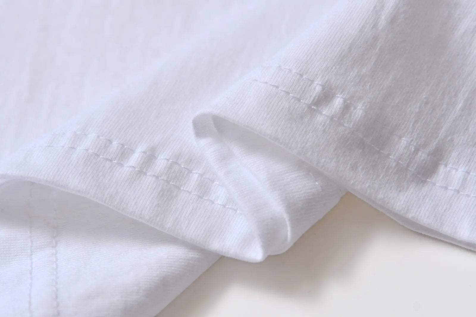 White cotton T-shirt overalls with a round neck and short sleeves, shown in a loose pullover style.