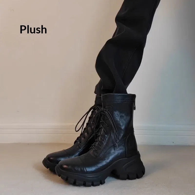 Black thick-soled motorcycle boots with back zipper, lace-up front, round toe, and rubber sole on a neutral background