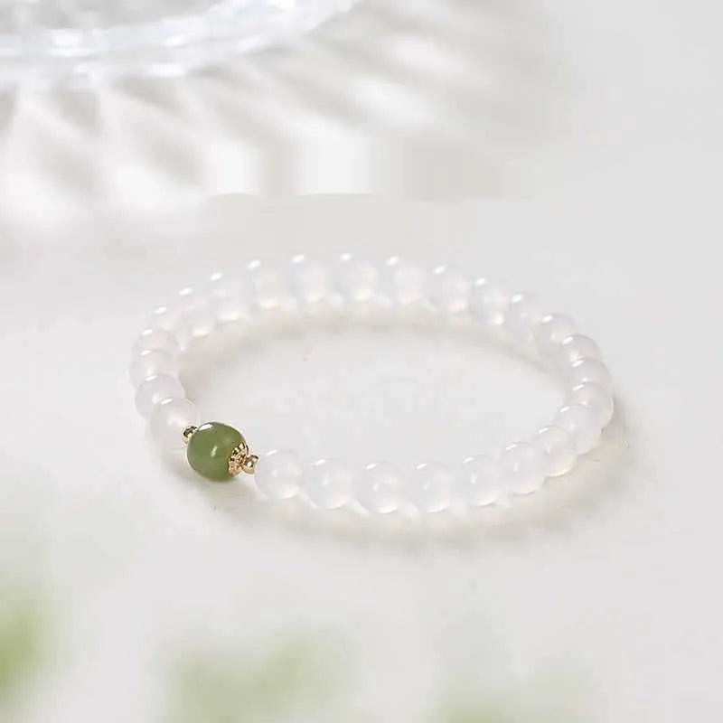 Handmade natural white agate and crystal bracelet with red cinnabar inlays on a wrist.