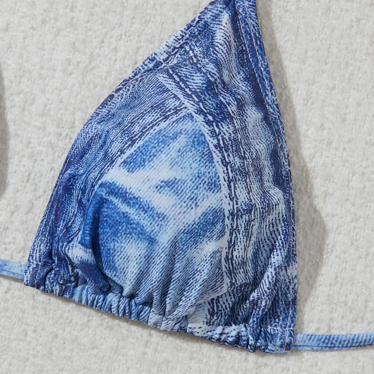 Denim blue printed women's two-piece bikini with thin straps, laid flat.