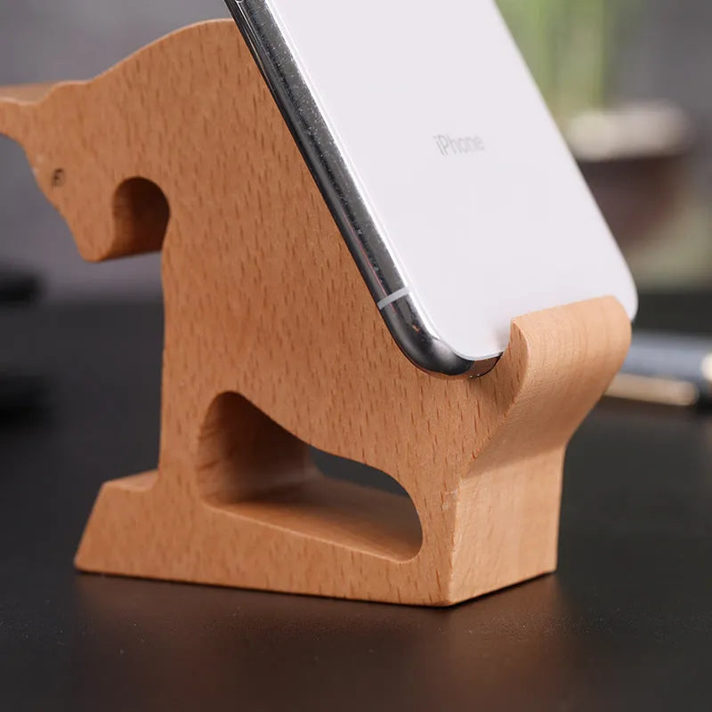 Sculpted beech wood lazy bracket phone holder with custom engraved text on a wooden desk.